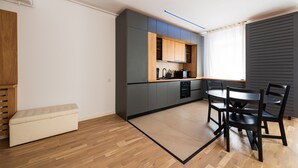 A modern kitchen with grey cabinets, a wooden countertop, and a dining area with a round table and chairs.
