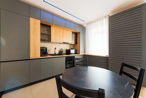 Una cucina moderna con mobili grigi, un piano di lavoro in legno e un tavolo in marmo nero.