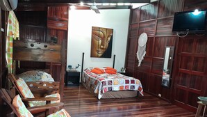 A room with a bed, wooden furniture, a ceiling fan, and a television. - Casas Guaney (Quepos)