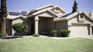 A two-story house with a garage, solar panels, and a well-maintained lawn.