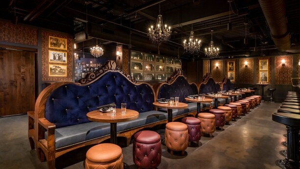 A bar with wooden booths, leather stools, and a bar counter.