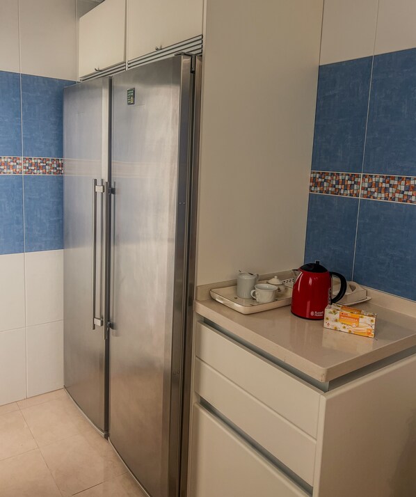 Una cocina con un refrigerador de acero inoxidable, una cafetera y una caja de café Manzanilla.