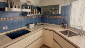 Una cucina moderna con piano cottura integrato, lavello e finestra con tende.