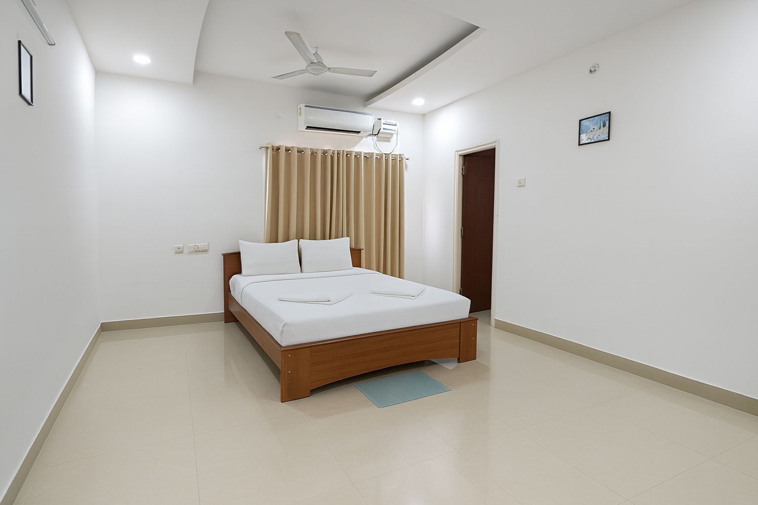 A modern bedroom with a wooden bed, beige curtains, a ceiling fan, and an air conditioning unit.