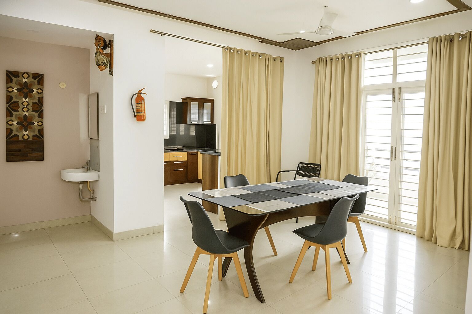 A modern dining area with a rectangular table, black chairs, and a kitchen in the background.