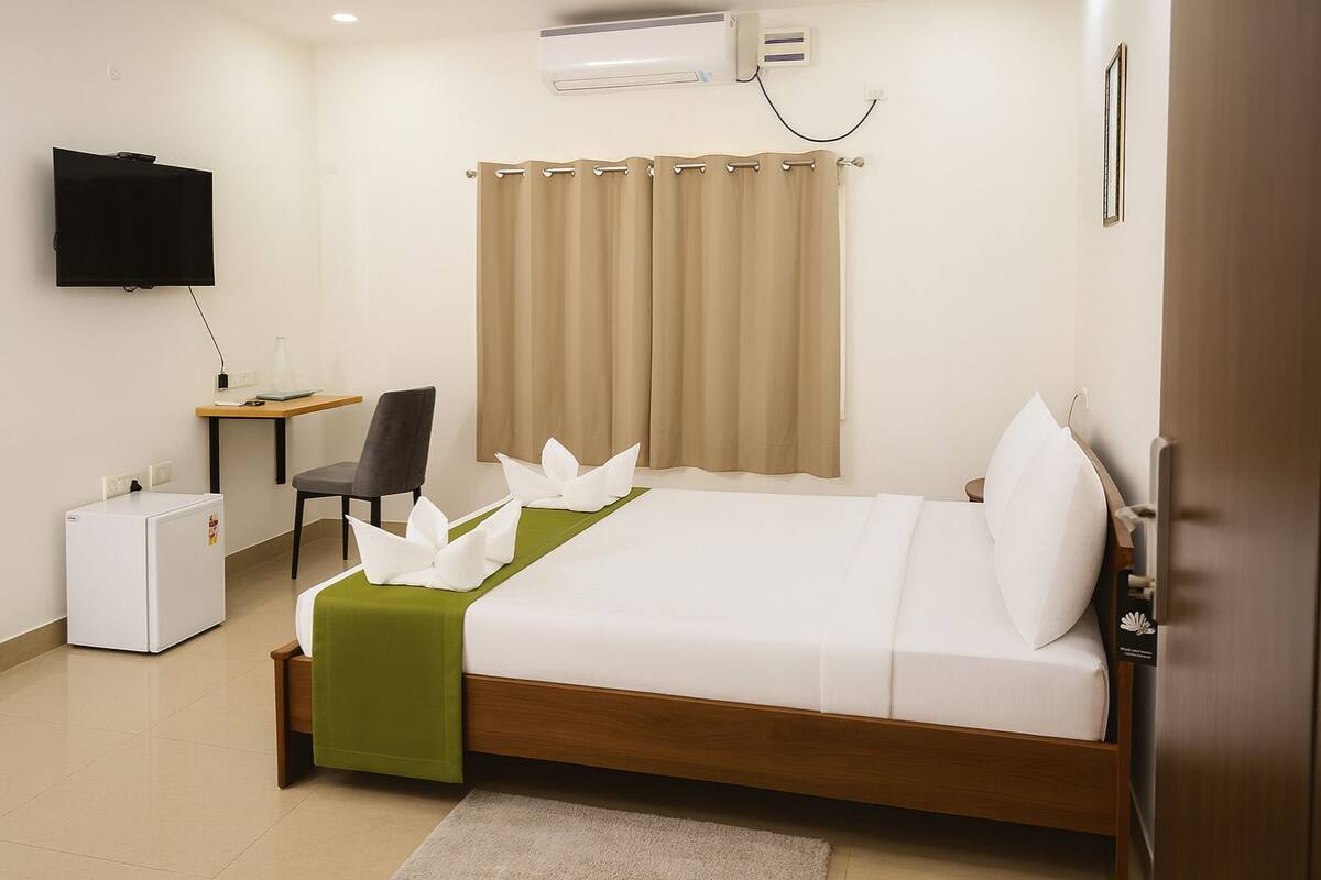 Ein Hotelzimmer mit Bett, Schreibtisch, Stuhl, Fernseher und Minikühlschrank.