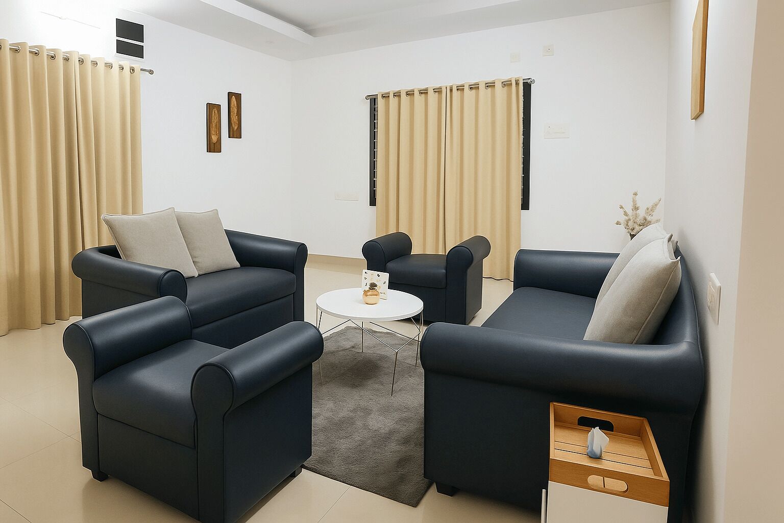 A modern living room with two dark sofas, a small white coffee table, and beige curtains.