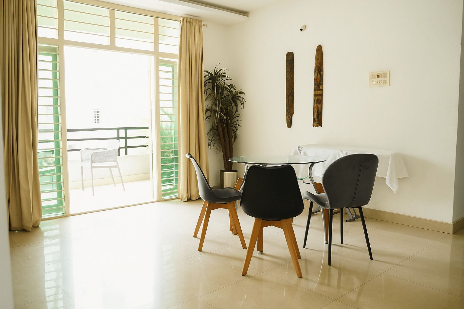 A dining area with a round table, four chairs, and a potted plant.