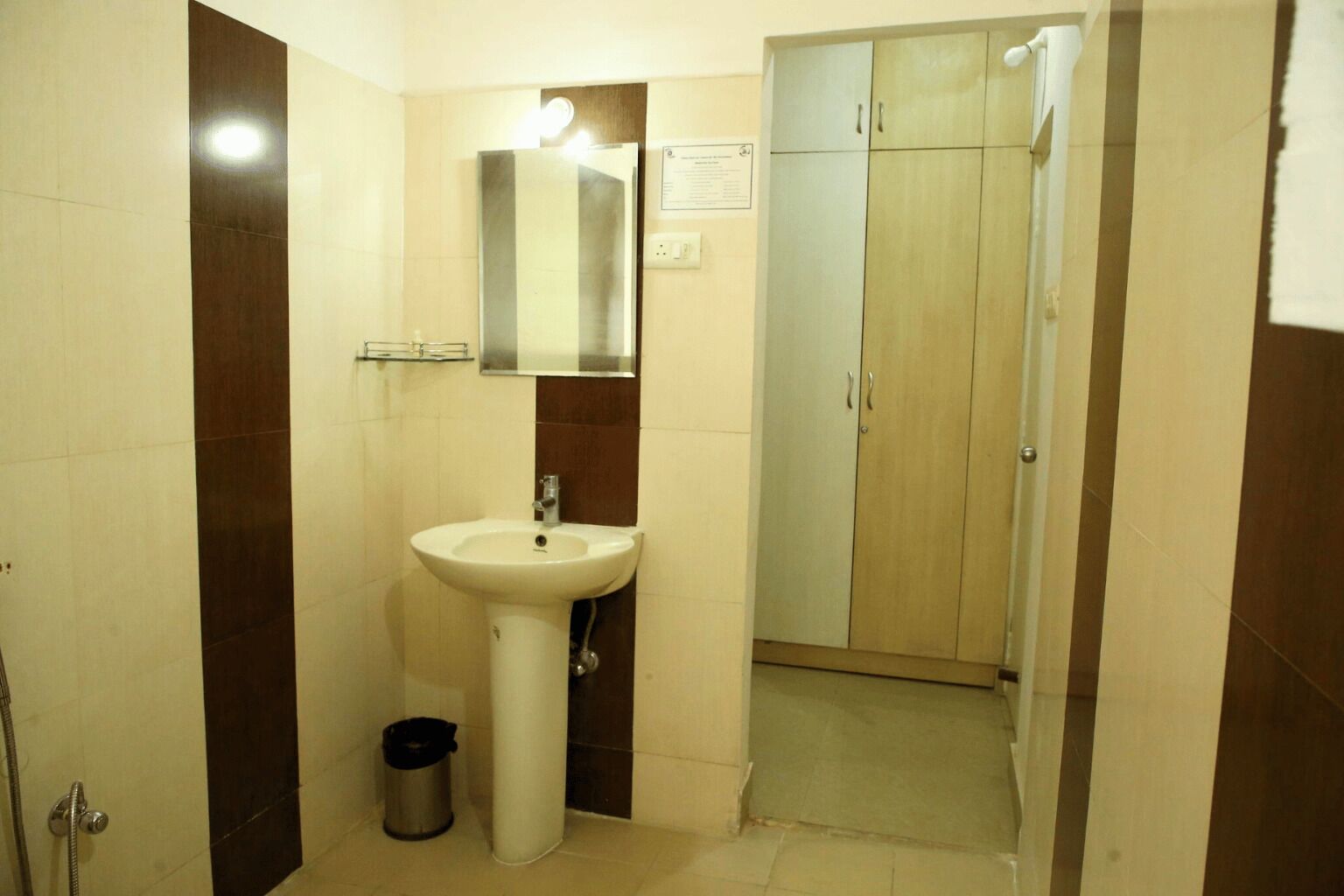 Une salle de bain avec un lavabo sur colonne, un miroir, un meuble et une poubelle.