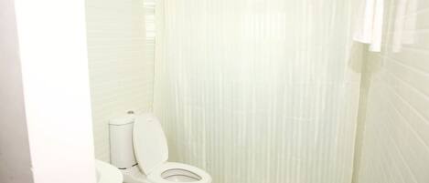 A small, white bathroom with a toilet, sink, and shower curtain.