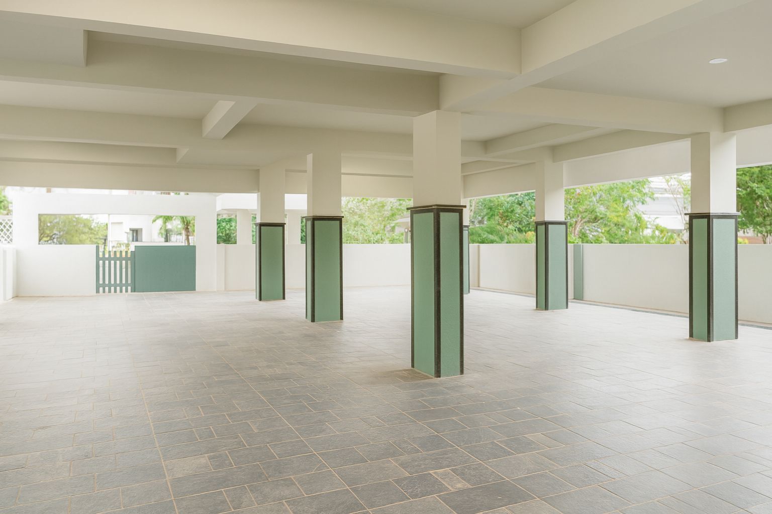 A spacious indoor area with a tiled floor and multiple green pillars.