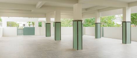A spacious indoor area with a tiled floor and multiple green pillars.