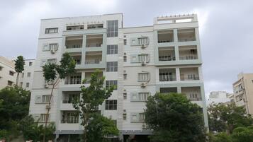 A multi-story residential building with balconies, large windows, and air conditioning units.