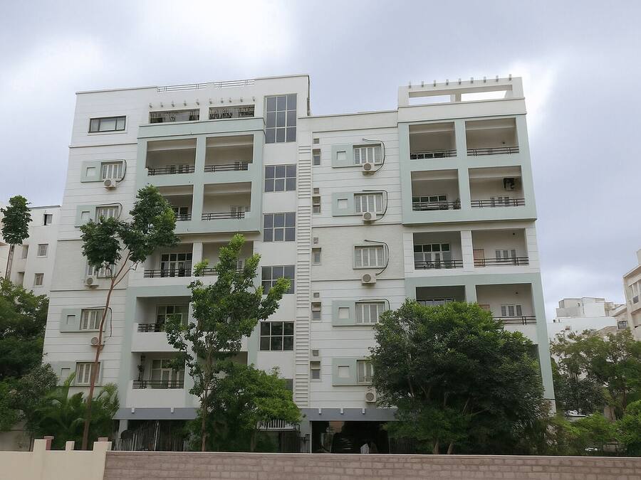 A multi-story residential building with balconies, large windows, and air conditioning units.