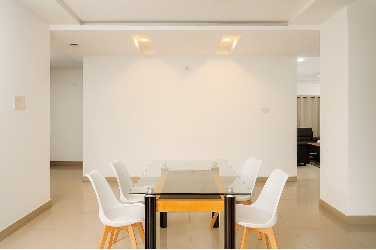 A conference room with a glass table, white chairs, and recessed ceiling lights.