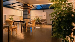 A modern dining area with a high ceiling, skylight, and wooden furniture. - White Fern Stays (Hyderabad)
