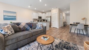 Un salon moderne avec un canapé, une table basse et une vue sur la cuisine et l’espace repas.
