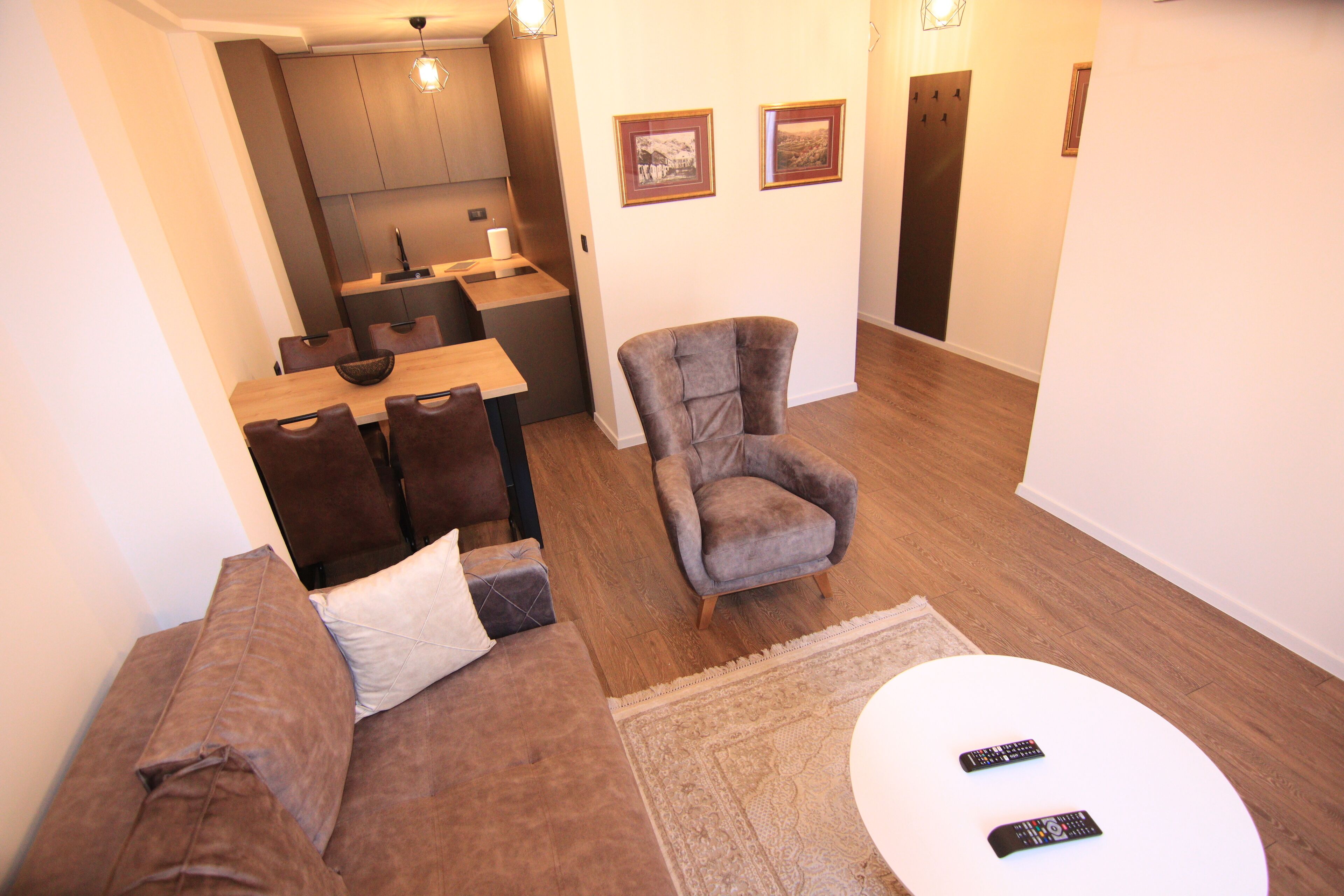 Una sala de estar con sofá, sillón, mesa de centro y mandos a distancia.