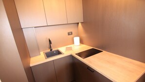 A compact kitchen with a sink, a countertop, and cabinets.