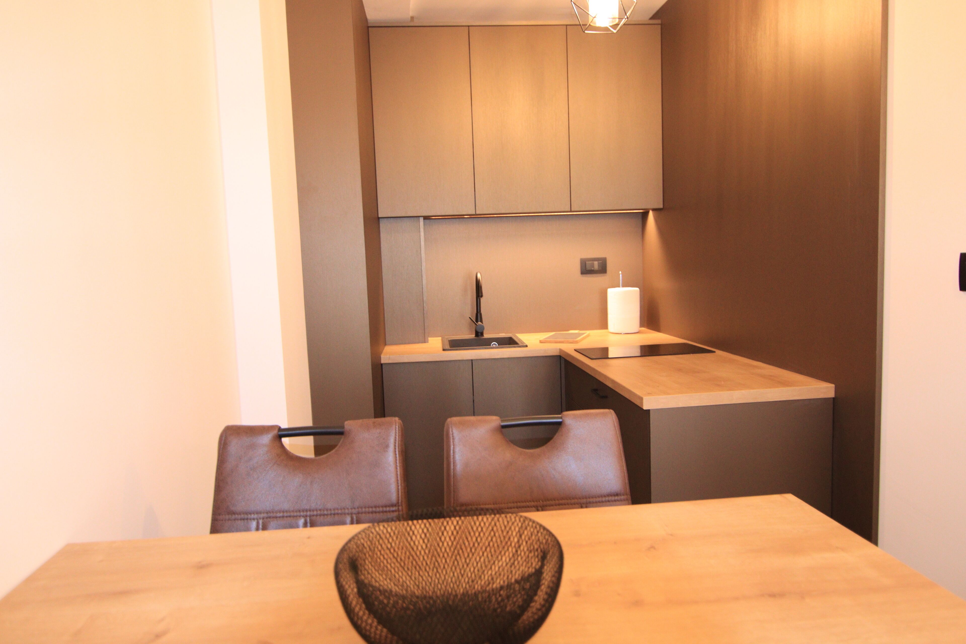 A compact kitchen with a sink, countertop, and two chairs.