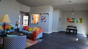 A spacious living room with a sofa, coffee table, and a dining area with chairs. - Heated 3BR • Furnished • WiFi • Laundry • Fort Sam w/ Wi-Fi & W/D (San Antonio)