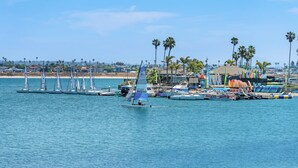 A marina with sailboats docked, palm trees, and a beach in the background. - Best View in Mission Bay, California (San Diego)