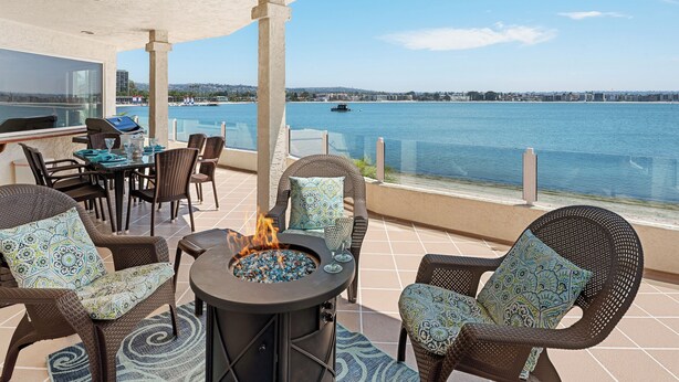 A patio with wicker furniture, a fire pit, and a view of the water. - Best View in Mission Bay, California (San Diego)