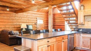 A log cabin interior with a kitchen, dining area, and a staircase. - Hill Cabin Hideaway, Romantic! Country Cabin for 2 (North Powder)