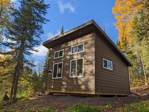 A wooden cabin with a gabled roof, multiple windows, and a chimney.