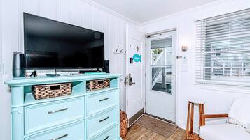 A room with a teal dresser, a flat-screen TV, and a wooden chair.