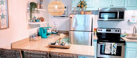 A modern kitchen with a central island, stainless steel appliances, and light blue cabinetry.