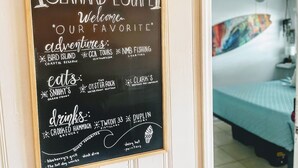 Pizarra con recomendaciones de atracciones, restaurantes y bebidas locales en una habitación con cama y obras de arte.
