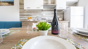 Une table à manger dressée avec des assiettes, une bouteille de vin et une plante en pot.