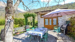 Un patio al aire libre con una mesa lista para comer, rodeado de follaje y vistas a la montaña.
