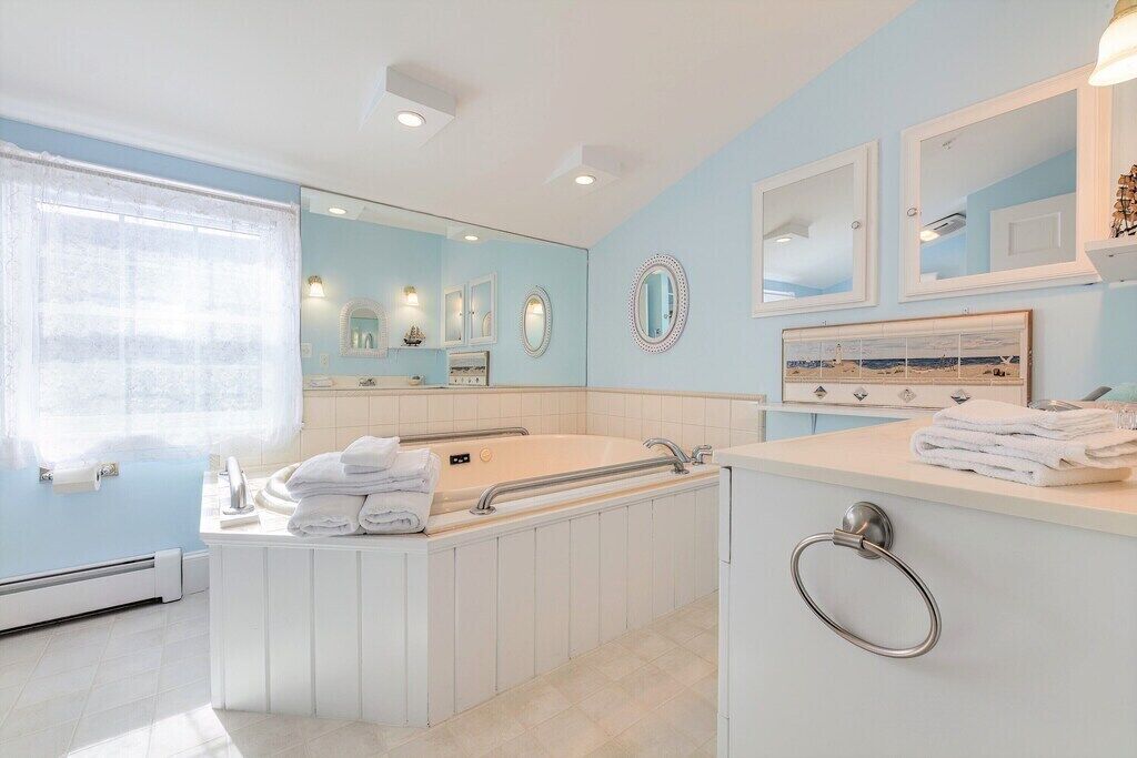 A modern bathroom with a freestanding bathtub, a vanity with a mirror, and a window with sheer curtains.