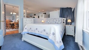 Quarto com cama, mesas de cabeceira, escrivaninha e cadeira.