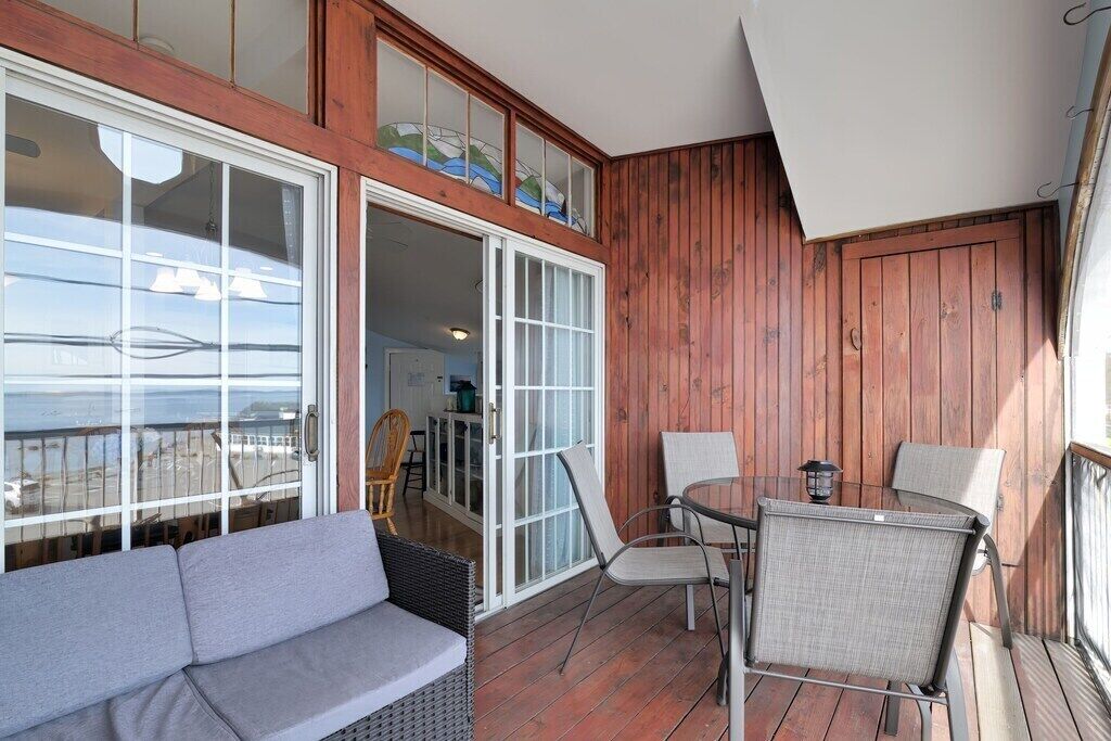 A balcony with a wooden floor, a sofa, and two chairs.