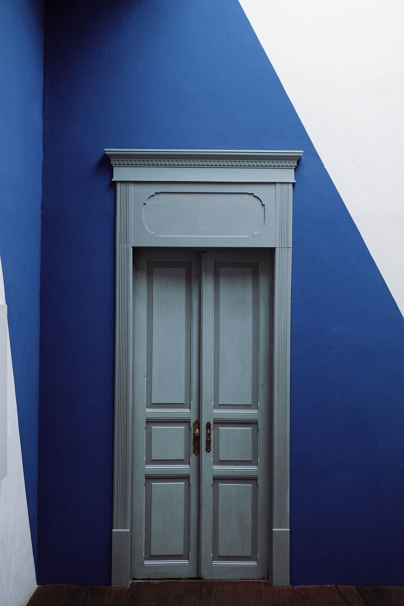 A double door with a classical design, set against a blue and white wall.
