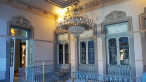 Uma escadaria imponente com elegantes balaústres azuis e um grande lustre.
