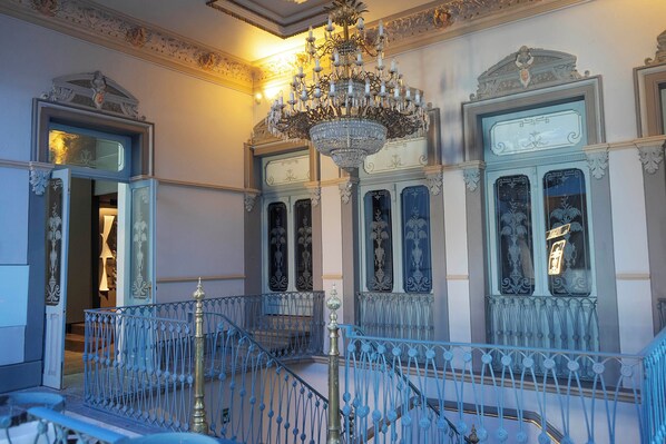A grand staircase with ornate blue railings and a large chandelier. - Palacio Julio Hotel (Puebla)