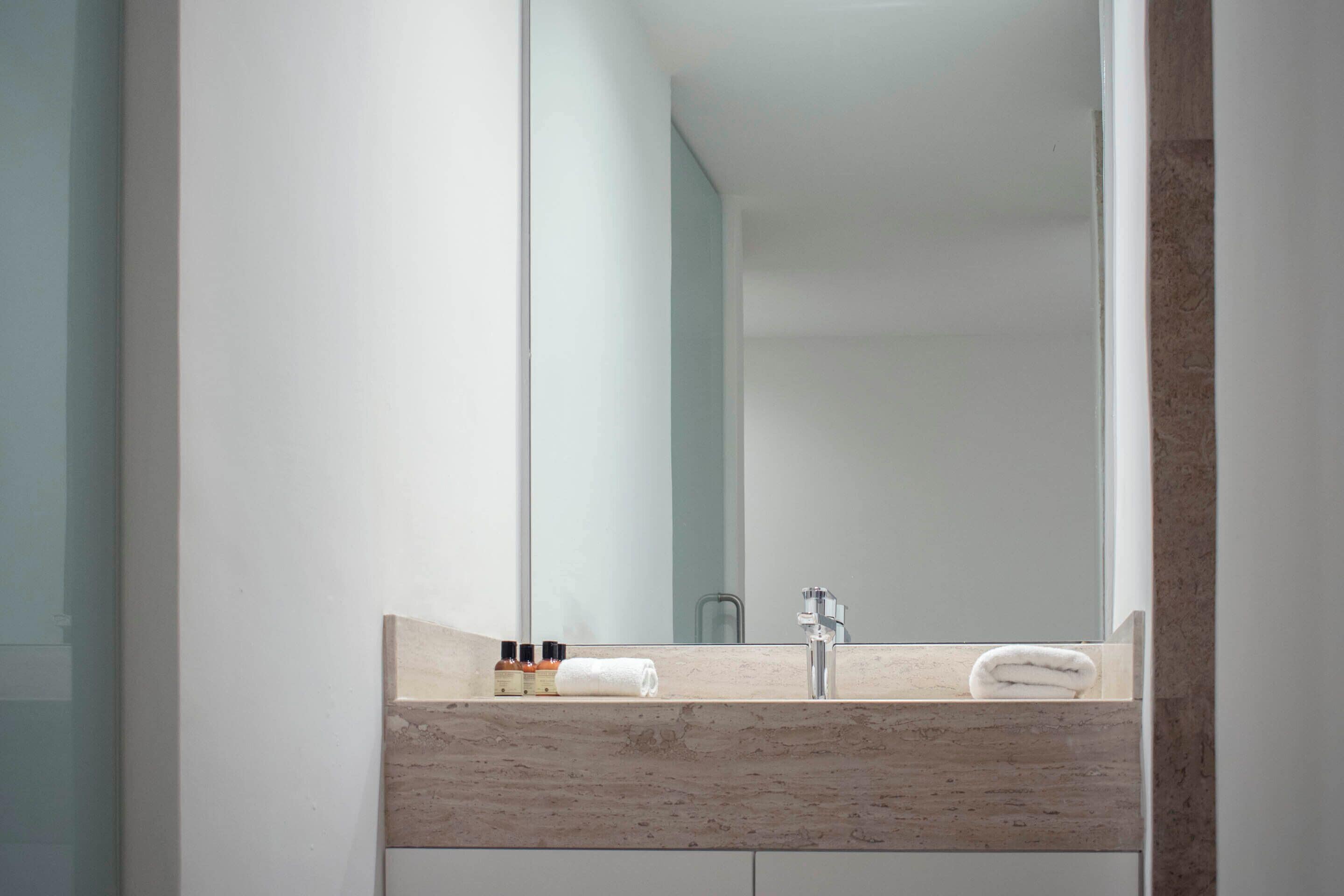 A bathroom with a large mirror, a sink, and a towel on the counter.
