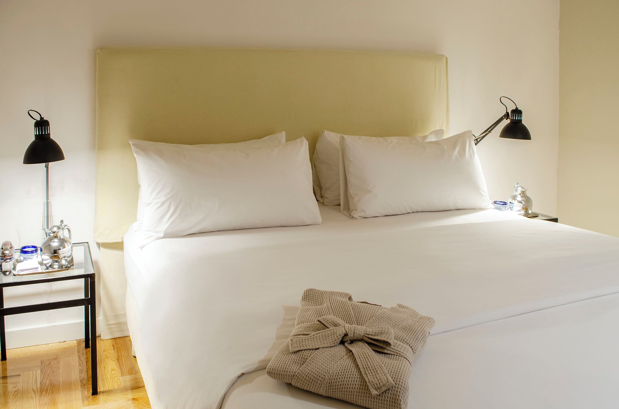 Hotelkamer met een groot bed, twee bedlampen, een nachtkastje met lamp en een opgevouwen handdoek op het bed.