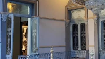 Un salón imponente con barandillas de metal decoradas, un candelabro y un espejo grande.