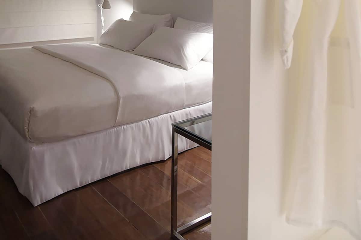 A modern bedroom with a large bed, a bedside table, and a hanging robe.
