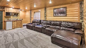 Ein Holzblockhaus-Interieur mit Ledersofa, Holzsärchen, einer Mikrowelle und einem gerahmten Bild an der Wand.