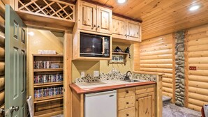 Eine kleine Küche mit Holzschränken, einer Mikrowelle, einem Spülbecken und einem Kühlschrank.