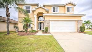 A two-story house with a garage, a covered entryway, and a well-maintained lawn. - Dog-Friendly Kissimmee Home w/ Lanai + Pool! (Kissimmee)