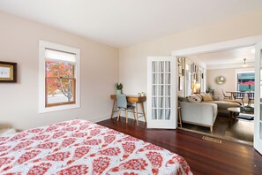 Un dormitorio con una cama grande, un escritorio y un sofá en la sala de estar contigua.