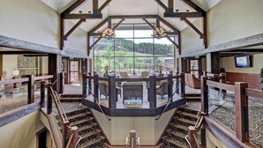 A spacious interior with a central staircase, wooden beams, and a view of a green landscape. - Ski-in/Out 10 Yards to  Lift Arcade Bowling Pool/Hot Tub Pool Table   (Breckenridge)