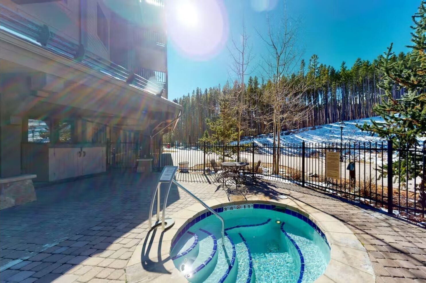 Ein Schwimmbecken mit einer gefliesten Kante, Sonnenschirm und Liegestuhl.